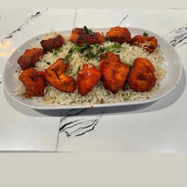 Chai Corner's Indian dish features vibrant red chicken tikka pieces served over a bed of white rice.